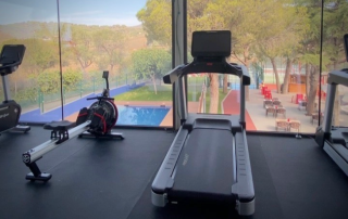 Panoramic view from the fitness room windows overlooking the padel courts and swimming pool at Can Teixidó Padel Club