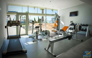Fully equipped fitness room at Hotel Atenea Port Mataró with a view of the terrace, swimming pool, and harbour
