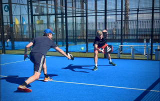 Two padel players at Bee-Padel Camp in Barceloneta reaching for the same ball, practicing teamwork and communication