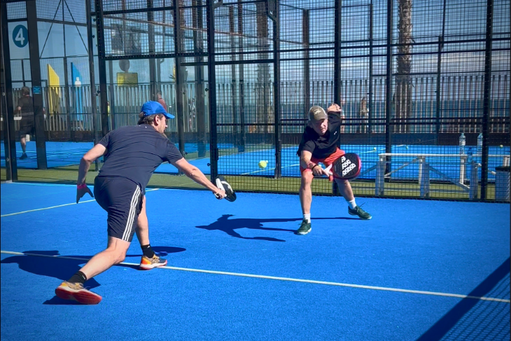 Two padel players at Bee-Padel Camp in Barceloneta reaching for the same ball, practicing teamwork and communication