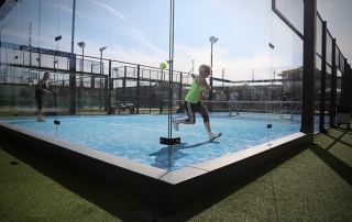 Panoramic view of the centre padel court at Masnou Ocata Padel Club with players in full action hitting balls off the wall