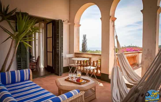 Shaded hammock on the private terrace of a room at Masia Can Casadellà with a silent view of gardens, mountains, and the sea