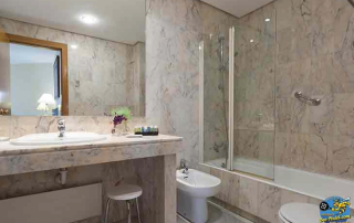 Basic marble bathroom with bathtub and amenities at URH Ciutat de Mataró