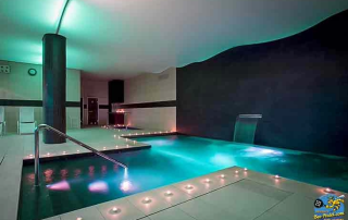 Indoor pool with view of sauna and steam bath at URH Ciutat de Mataró wellness area